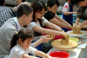 Chengdu, China - April 23, 2005: Students seated on stools using potters wheels learn how to make pottery during an outdoor class in the city's expansive Cultural Park