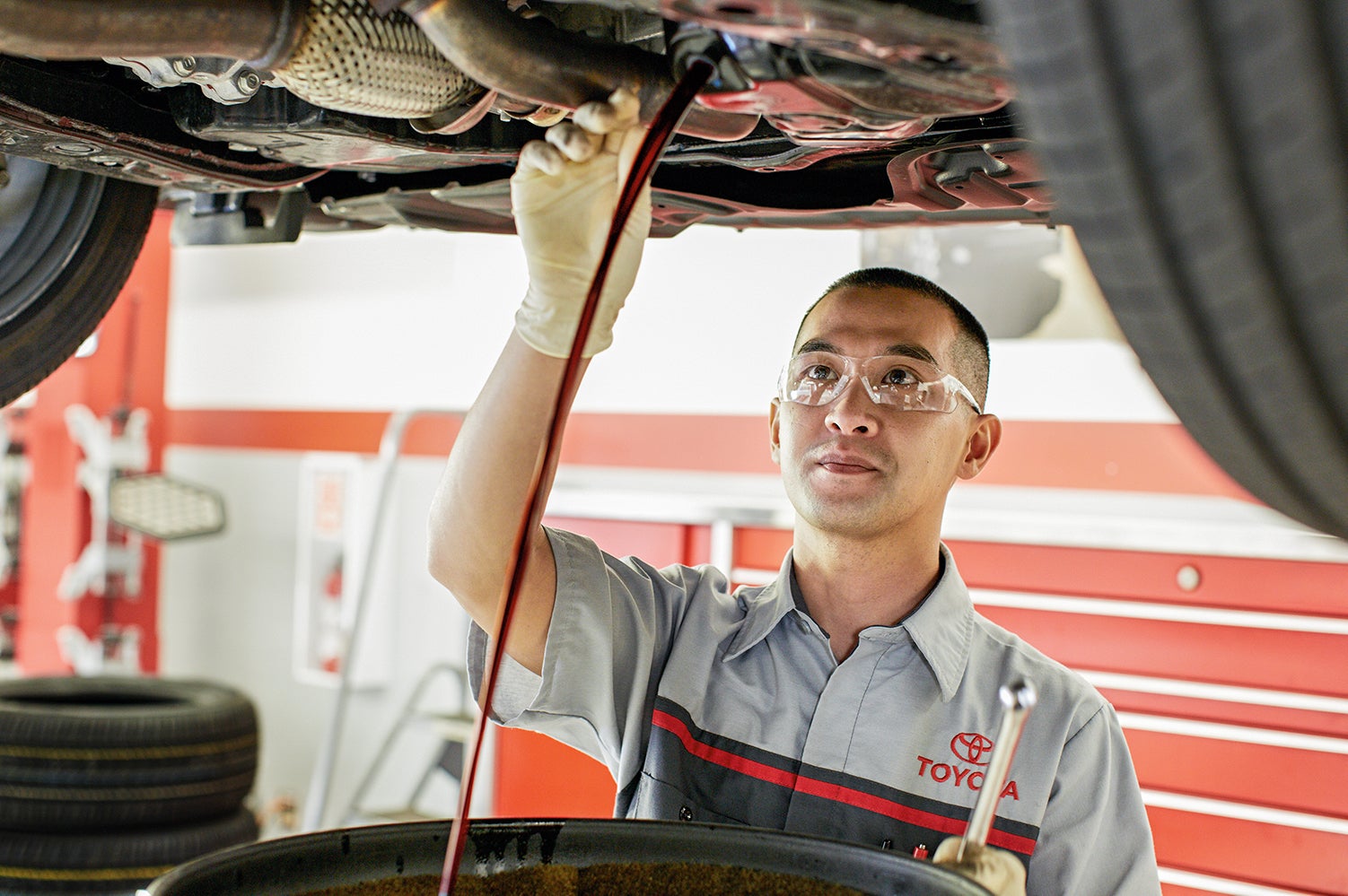 Benefits of Changing Your Toyota’s Oil at Bennett Toyota in Allentown | Toyota service technician draining old oil out of engine