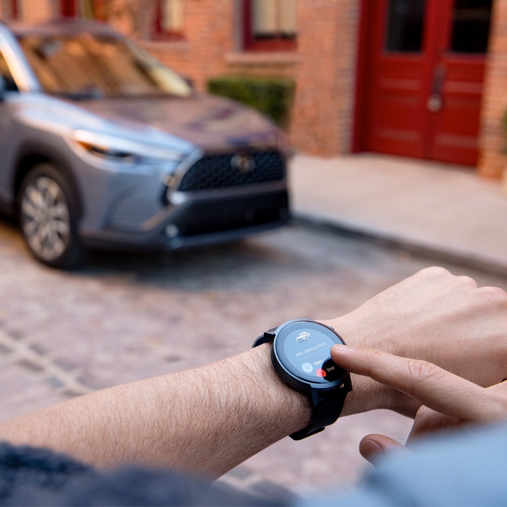 Model Features of the 2022 Toyota Corolla Cross at Bennett Toyota | Close up of a Man Looking at His Smart Watch Starting his Corolla Cross in the background