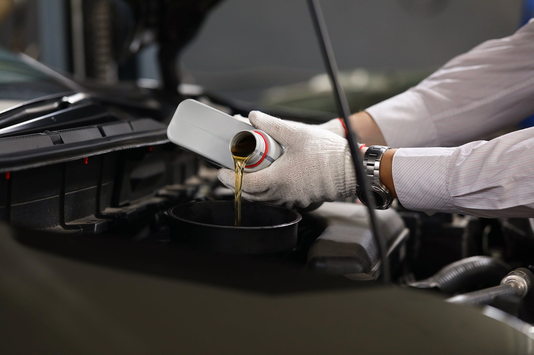 Difference between synthetic oil & conventional oil at Bennett Toyota | Toyota mechanic refilling oil in a Toyota vehicle
