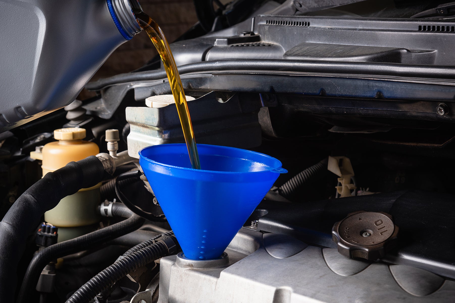 Difference between synthetic oil & conventional oil at Bennett Toyota | Mechanic filling up oil