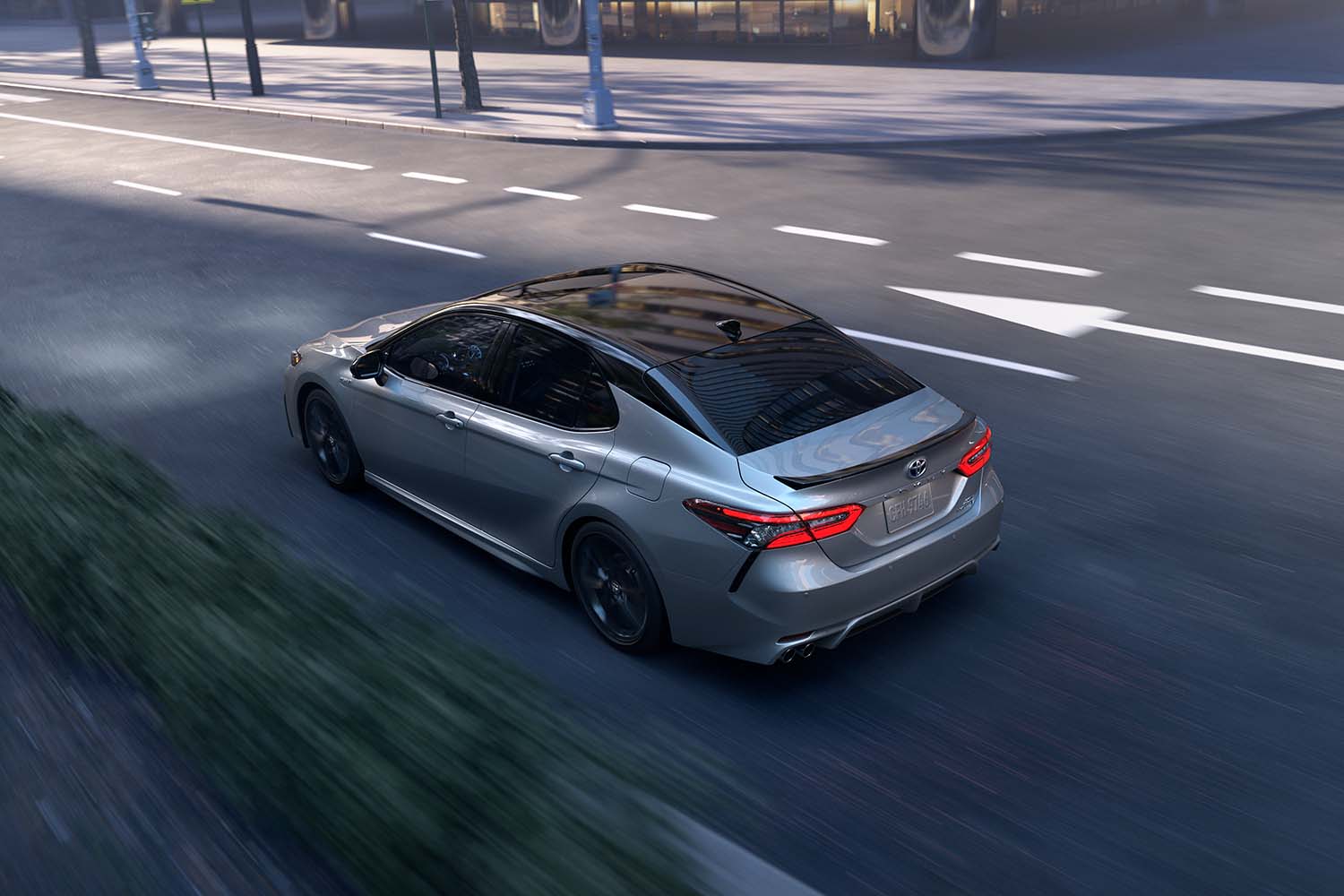 Toyota Hybrid for Everyone at Bennett Toyota | 2022 Toyota Camry Hybrid rear driving through the town